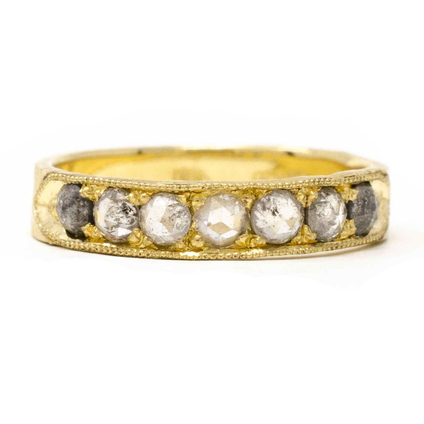 An 18k yellow gold band ring with a milgrain finish, featuring a series of round grey diamonds set close together.