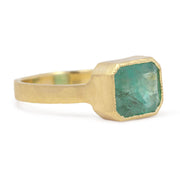 Gold ring with a green gemstone on a white background