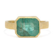 Gold ring with a green gemstone on a white background