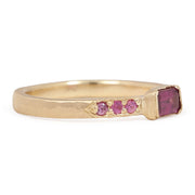 Gold ring with pink gemstones on a white background