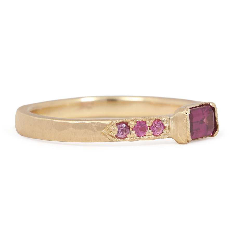 Gold ring with pink gemstones on a white background