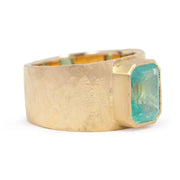 Gold ring with a large green gemstone on a white background