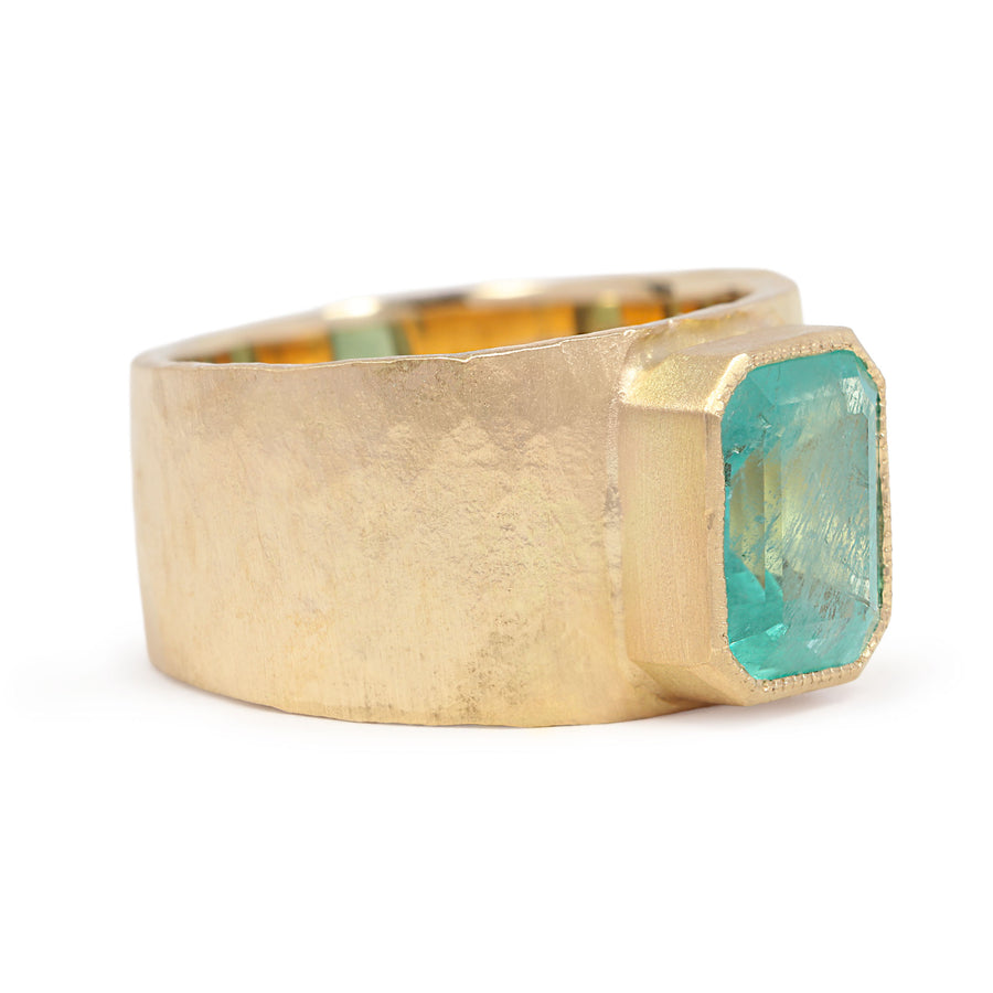 Gold ring with a large green gemstone on a white background