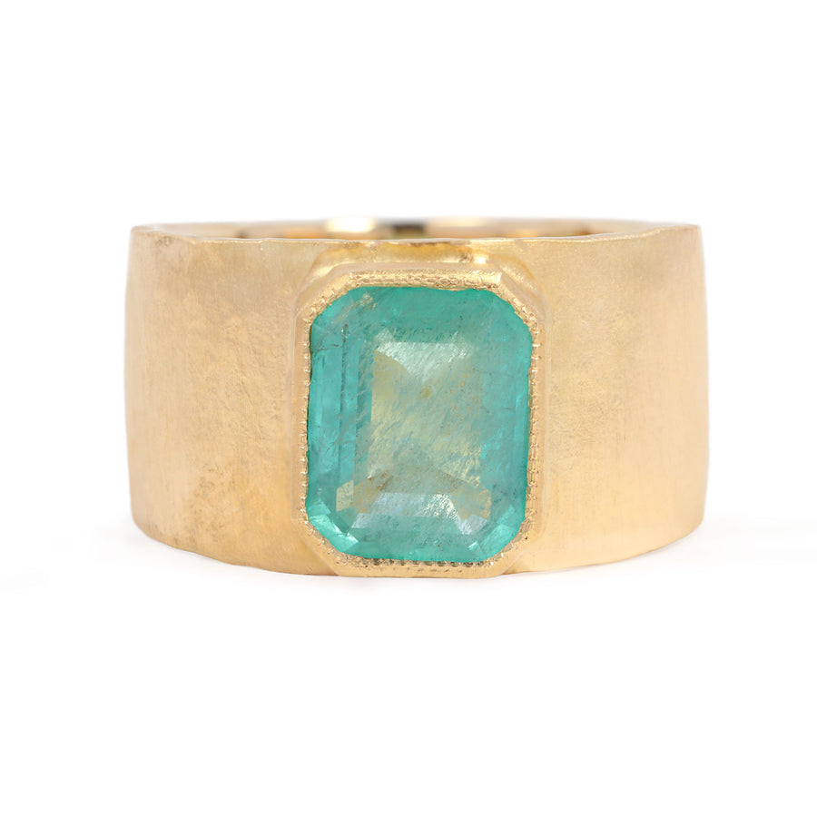 Gold ring with a green gemstone on a white background