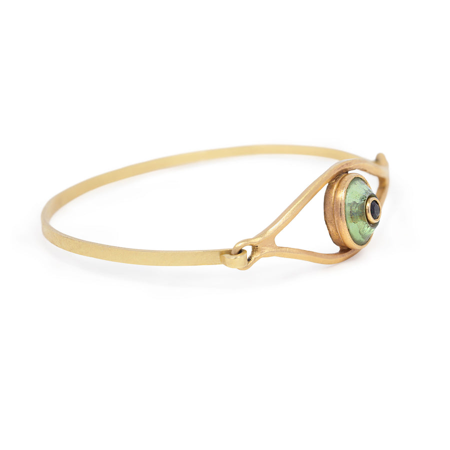 Gold bracelet with a green eye charm on a white background