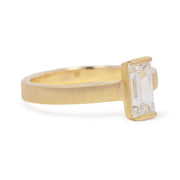 Gold ring with a rectangular diamond on a white background
