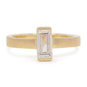 Gold ring with a rectangular diamond on a white background