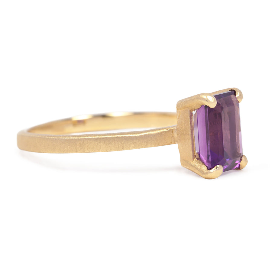 Gold ring with a purple gemstone on a white background