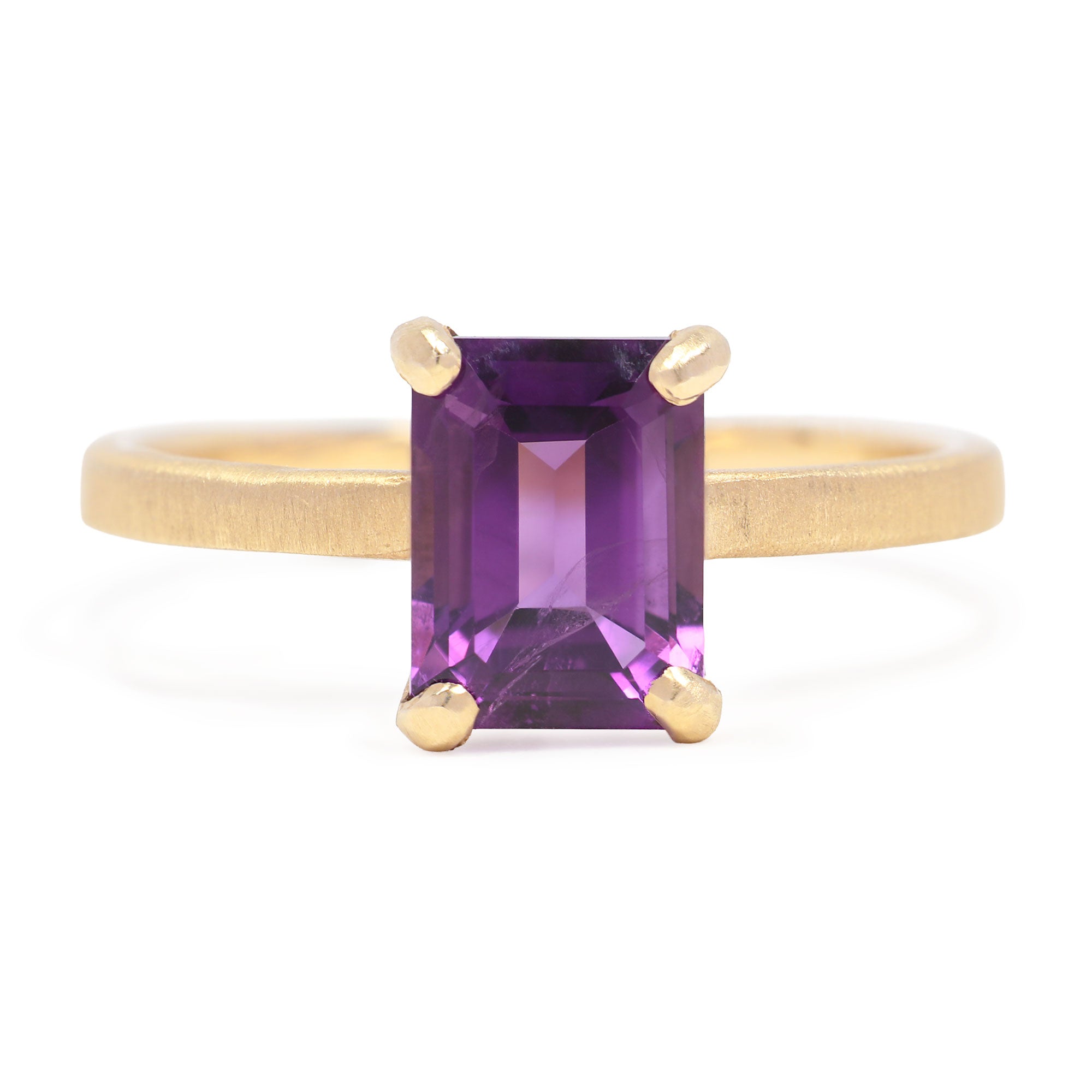 Gold ring with a purple gemstone on a white background