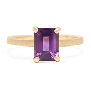 Gold ring with a purple gemstone on a white background
