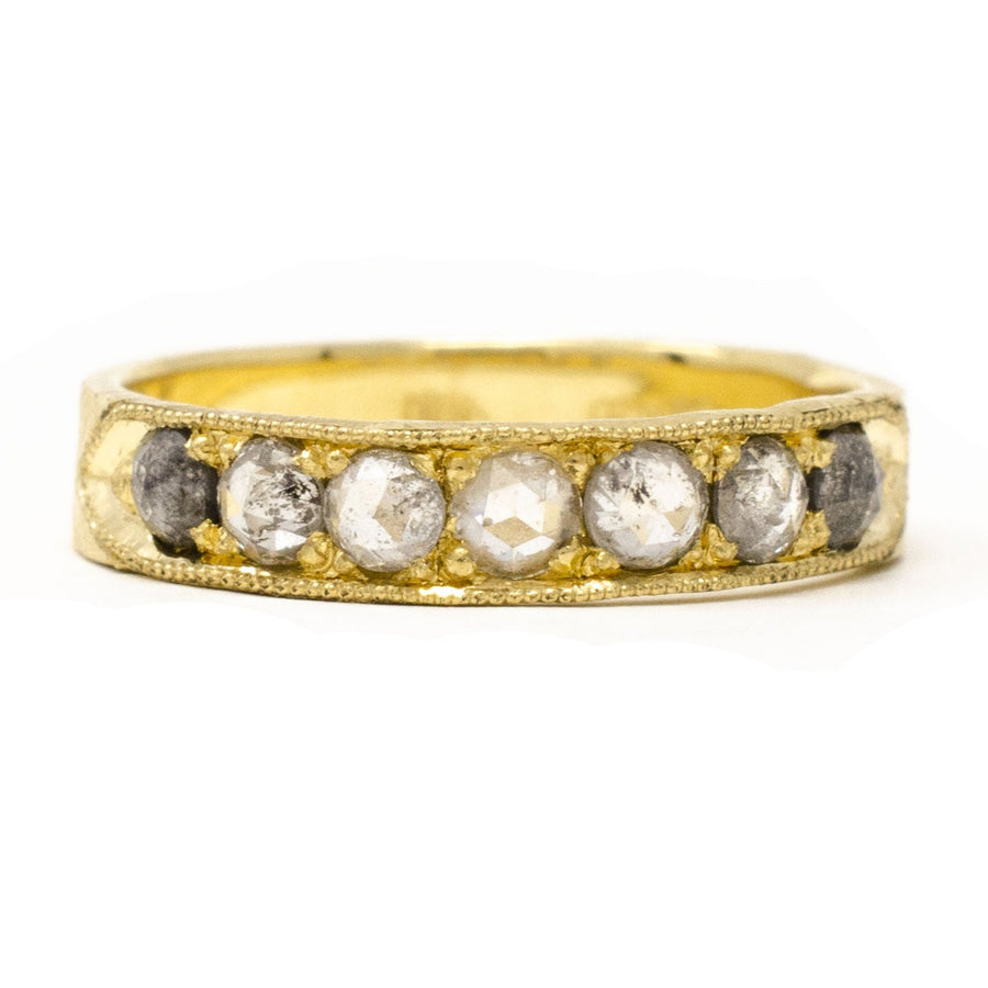 An 18k yellow gold band ring with a milgrain finish, featuring a series of round grey diamonds set close together.